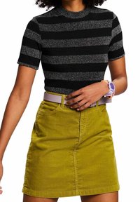 Czarna i szara bluzka w paski z krótkim rękawem i zaokrąglonym dekoltem, zestawiona z jasnoliściem spódnicą sztruksową z kieszeniami i paskiem.