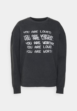 Zwarte sweatshirt met witte tekst: "JE BENT GELIEFD," en "JE BENT WAARD," in verschillende groottes en oriëntaties. Ribgebreide mouwen en halslijn.