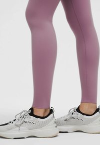 Heledad lilla retuusid venivast kangast, koos valgete ja mustade tossudega, millel on võrgupaneelid ja kummist tald.