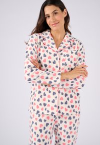 Fleece pyjama set met een crèmekleurige achtergrond versierd met roze en marineblauwe hartpatronen; bevat een knoopjesoverhemd met kraag en borstzak.