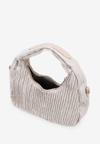 Bolso cremoso texturizado con un diseño plisado, asa curva, cierre con cremallera y forro de tela. Presenta acentos de hardware en dorado.