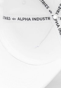 Căciulă de baseball albă cu logo-ul negru "Alpha Industries" pe banda interioară. Material neted, formă structurată și cusături vizibile.