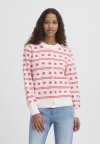 Cardigan rose clair avec des motifs de cœurs rouges et des rayures, doté d'un col rond et de six boutons, confectionné dans un matériau en maille douce.