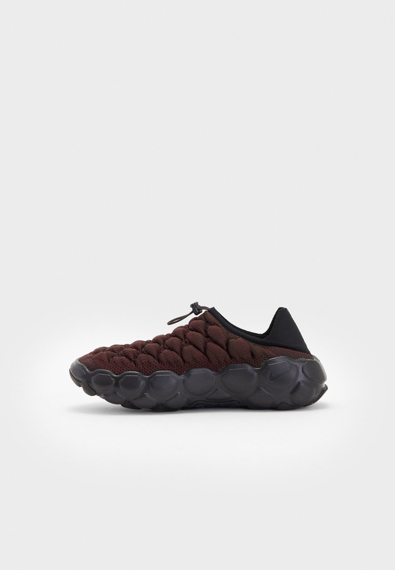 Sneakers wsuwane z ciemnoczerwonym plecionym wierzchem i czarnymi akcentami. Okrągła, teksturowana podeszwa z motywem plastra miodu zapewniająca przyczepność.
