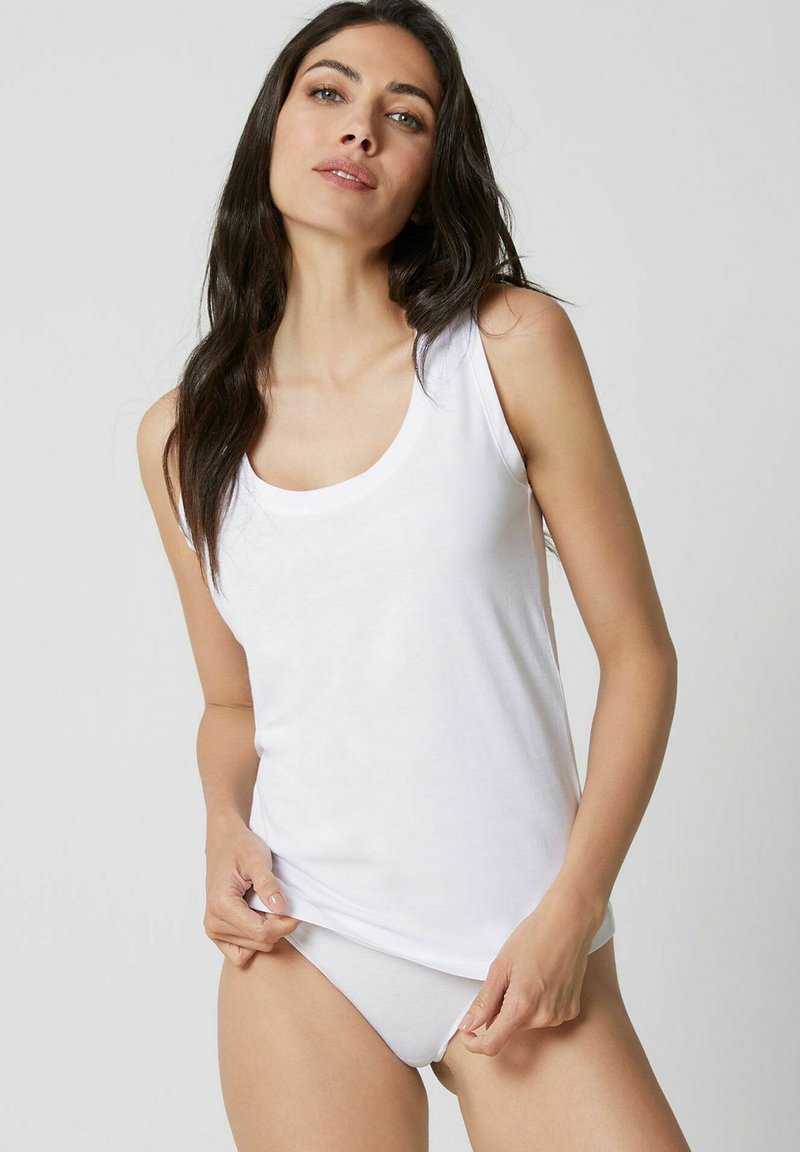 White sleeveless tank top made of soft fabric, featuring a round neckline and a relaxed fit, paired with matching white underwear.