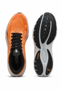 Zapatillas de correr naranja brillante con cordones negros, parte superior de malla transpirable y suelas de goma en blanco y negro etiquetadas con "PUMAGRIP" y "Nitro".