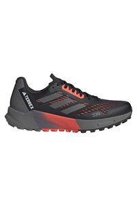 Zwarte en rode Adidas Terrex trailrunning-schoen met grijze strepen, een gestructureerde zool en "320" gedrukt nabij de teen.