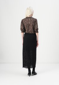 Halenka s leopardím potiskem a balónovými rukávy, v kombinaci s dlouhou černou krajkovou sukní. Černé ponožky a boty na podpatku dotvářejí outfit.