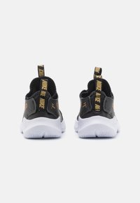Baskets de sport noires avec une tige texturée, un col élastique et une semelle en caoutchouc blanche. Présente un logo Nike et une languette avec le texte "NIKE".