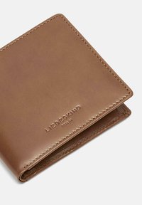 Brązowy skórzany portfel z wytłaczanym logo, gładką fakturą i kontrastującym przeszyciem na krawędziach, o składanej konstrukcji.