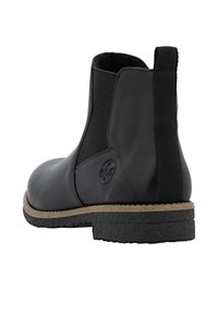 Bottines en cuir noir avec panneaux élastiques sur les côtés, semelle en caoutchouc texturée et accent en liège autour de la base. Logo affiché sur le côté.