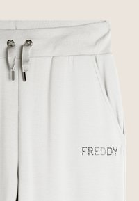 Lichtgrijze joggerbroeken van zachte stof, met een trekkoord in de taille, zijzakken en een decoratief rhinestone 'FREDDY' logo.