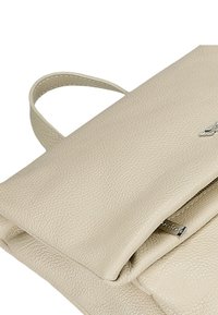 Borsa a mano in pelle beige con finitura testurizzata, dotata di chiusura a pattina e un piccolo manico laterale. Dettaglio del logo in metallo argentato incluso.
