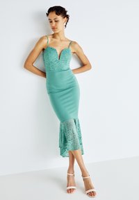 Rochie verde menta cu un corset din dantelă, gât adânc și tiv evazat din dantelă. Bretele subțiri și o siluetă ajustată amplifică designul său elegant.