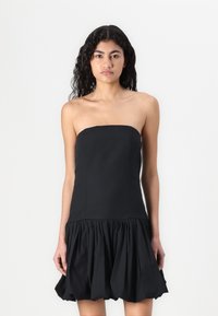 Robe noire sans bretelles avec un corsage ajusté et une jupe évasée froncée. Fabriquée dans un tissu lisse avec une finition mate.