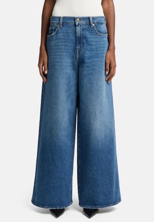 Lichtblauwe wijdvallende jeans van denim, met een hoge tailleband, voorzakken en een rafelige zoom, gecombineerd met puntige zwarte schoenen.
