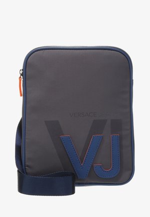 Bolso cruzado compacto de color gris oscuro con ribetes azul marino, correa ancha ajustable y grandes letras "VJ" en azul en la parte frontal.