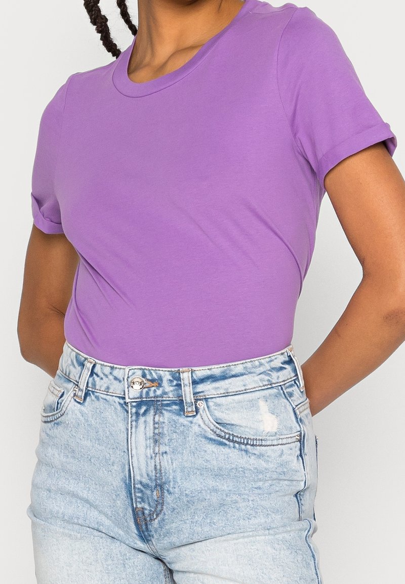 Fialové tričko s krátkým rukávem vyrobené z měkké bavlny, s kulatým výstřihem a přiléhavým střihem, spojené s světle modrými potrhanými džíny šortkami.