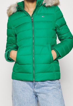 Grüne Steppjacke mit Reißverschluss vorne, seitlichen Taschen und einer mit Fell gefütterten Kapuze. Verfügt über horizontale Nähte und gerippte Bündchen.