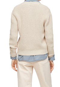 Bežový pletený svetr s dlouhými rukávy, ribbovaným lemem, nošený přes modrou a bílou pruhovanou košili s límcem. Strukturovaná tkanina s otevřeným úpletem.