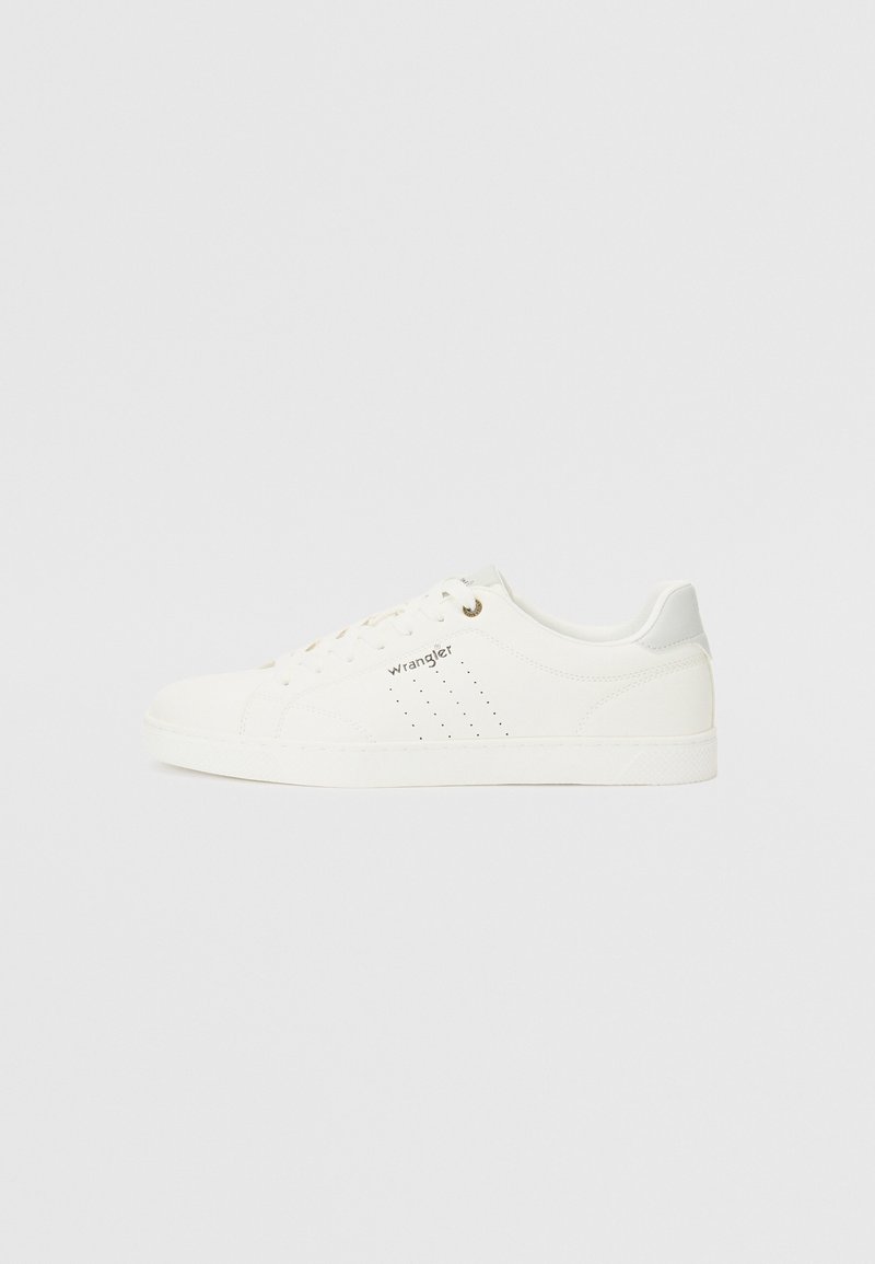 White leather sneakers with perforated accents, flat white sole, beige laces, and a gold logo on the side. Soft textured finish.