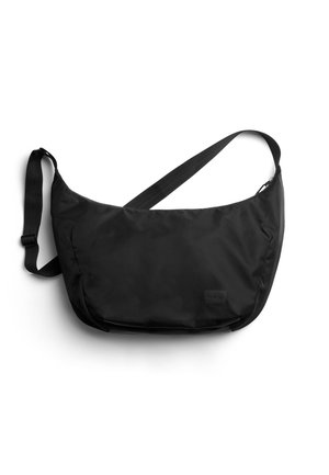 Schwarze Nylon-Umhängetasche mit verstellbarem Riemen und kleinem rechteckigem Markenetikett vorne vor weißem Hintergrund.