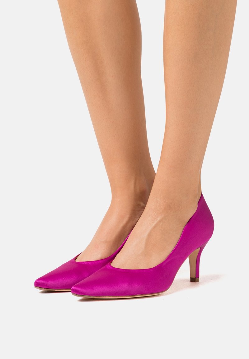 Scarpe con tacco alto in satin fucsia brillante, con punta appuntita e tacco sottile. Texture liscia e design minimalista.