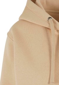 Felpa beige con cappuccio, dotata di un cordino, con un finish testurizzato, tessuto morbido e vestibilità rilassata, che mette in evidenza un cappuccio senza cuciture e dettagli di cucitura.
