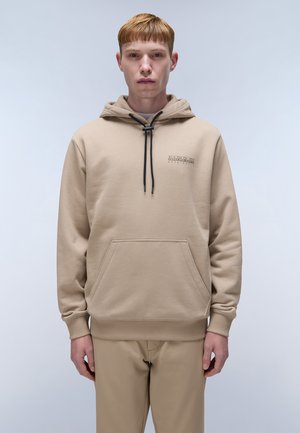 Haut à capuche beige avec une poche avant, un cordon de serrage à la capuche et un petit logo sur la poitrine. Tissu lisse, coupe décontractée, associé à un pantalon assorti.