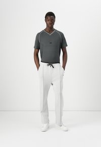 Gray textured short-sleeve T-shirt with white accents paired with light gray tapered pants and white sneakers. Minimalistic design.