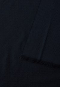 Sötét tengerészkék sál, dombornyomott mintával és rojtos szegéllyel. Anyaga puha és könnyűnek tűnik.