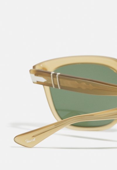 Óculos de sol em padrão tartaruga com lentes verdes, apresentando uma armação robusta, detalhes em prata e uma haste afunilada com detalhe da marca.