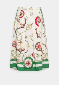 Jupe plissée blanche avec un imprimé nautique comportant des ancres, des compas et des cordes. Ourlet vert avec des couleurs d'accent rouge et rose.