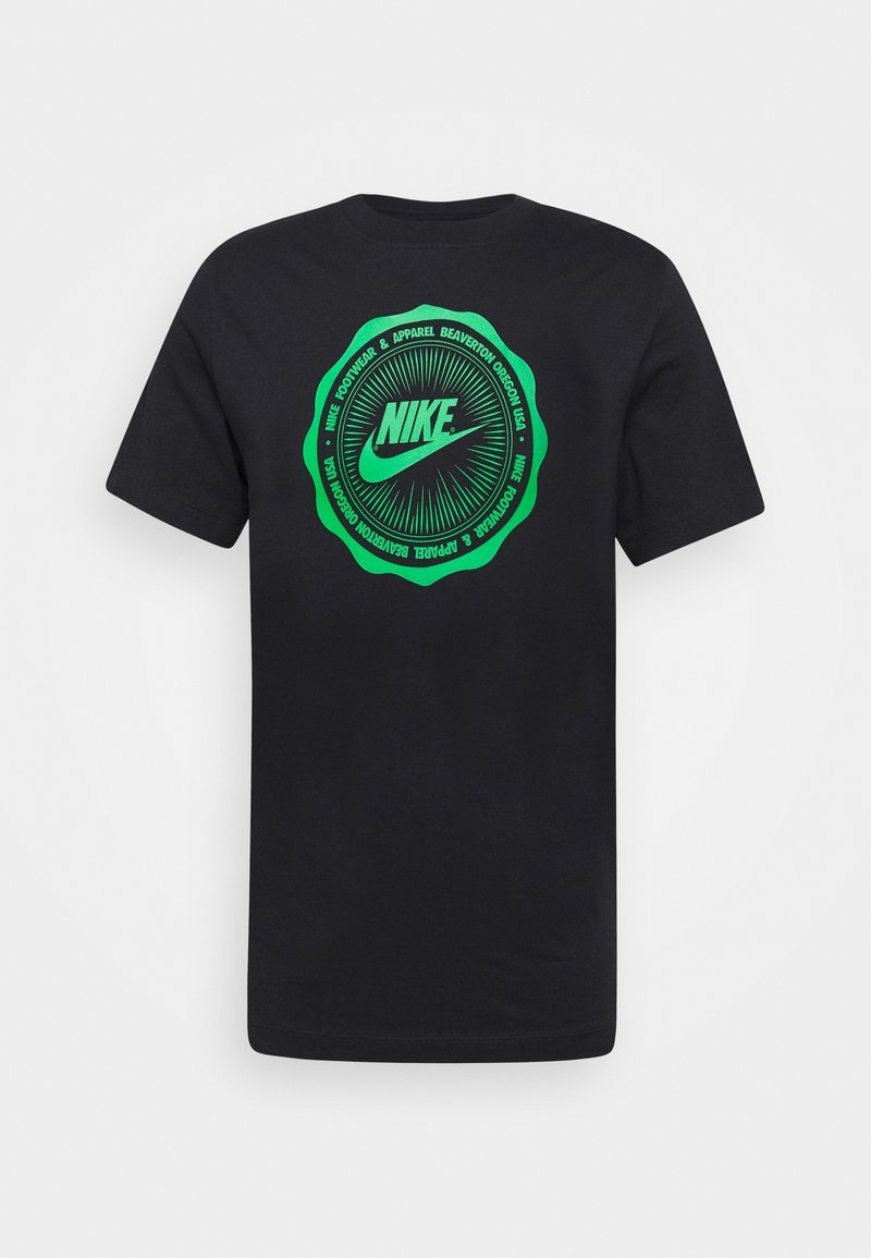 Černé bavlněné tričko s kulatým zeleným grafickým vzorem uprostřed, na kterém je text "Nike", vycházející linie a detaily značky kolem okraje.