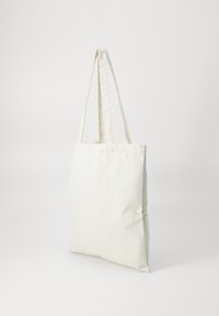 Sac en toile, couleur crème, forme rectangulaire, deux poignées en tissu, sans motifs ni accessoires visibles, texture douce, design simple.