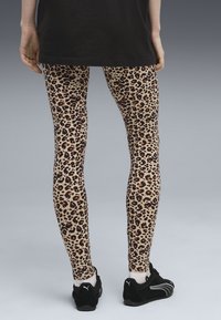 Luipaardprint leggings hebben een beige basis met zwarte en bruine vlekken. gedragen met zwarte sportschoenen, is de look casual en strak.