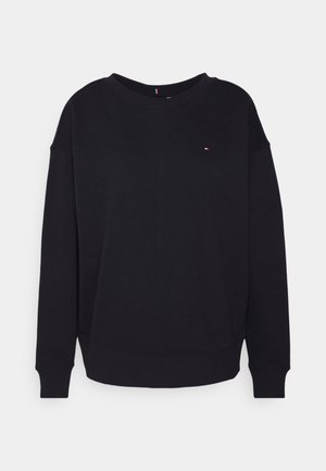 Zwarte crewneck-trui met lange mouwen en een klein rood-wit-blauw logo op de linkerborst tegen een effen achtergrond.