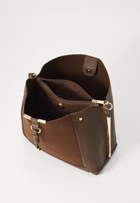 Borsa a mano in pelle marrone con una texture liscia, dotata di un compartimento con zip, hardware in tono oro e un design strutturato.