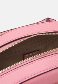 Sac synthétique texturé rose avec deux compartiments zippés. Zips et accents dorés. L'intérieur est beige avec une étiquette de marque.