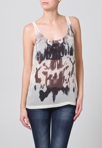 Haut sans manches léger en tissu crémeux transparent avec un motif abstrait en aquarelle brun et noir. Encolure ronde et coupe décontractée.