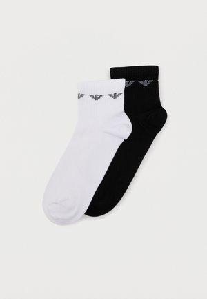 Üks paar musti ja üks paar valgeid pahkluu sokke, kummalgi väikese musta logomustriga varruka lähedal.