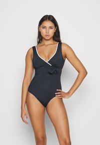 Black one-piece swimsuit with a deep V-neck, white trim, and a front knot detail. Made of smooth fabric, featuring a fitted silhouette.