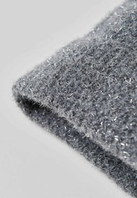 Grijze stof met een vachtachtige textuur en metalen zilveren draden verweven, wat een zachte, glinsterende uitstraling creëert.