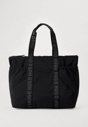 Sac cabas noir HUGO avec deux longues anses imprimées du logo, une fermeture zippée sur le dessus et des poches latérales froncées, présenté sur un fond clair.