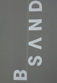 Gray cotton shirt with bold white printed text. Features a vertical alignment of letters, with stitching visible along the side seam.