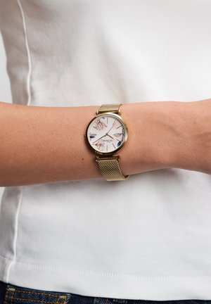 Horloge met gouden meshband en een ronde wijzerplaat, voorzien van een witte wijzerplaat met bloemmotieven en blauwe accenten.