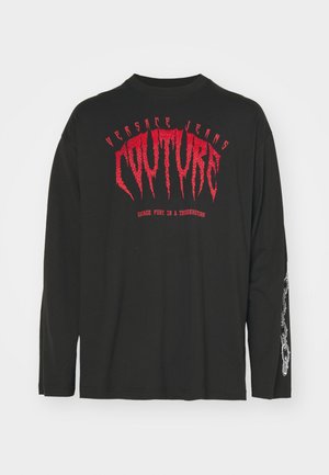 Sort langærmet T-shirt lavet af bomuld med fede røde grafik og teksten "COUTURE". Detaljer inkluderer grafisk design på ærmet.