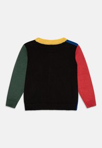 Megzta megadžeris su daugiaspalvėmis rankovėmis: žalia, raudona, mėlyna, ir juodas korpusas, su tekstūruotu geltonu apykakle ir guma viršuje.