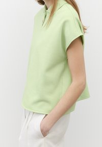Koszulka polo z krótkim rękawem w jasnym zielonym kolorze, wykonana z bawełny o strukturalnym wykończeniu, z zapięciem na guziki i luźnym krojem.