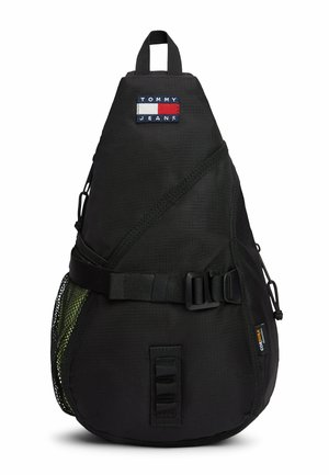 Schwarzer dreieckiger Sling-Rucksack mit Tommy Jeans Logo-Patch, verstellbarem Schnallenriemen, Netz-Seitentasche und Cordura-Stoffetikett.
